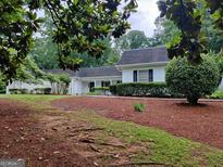 Traditional white home with a lush, landscaped front yard and manicured hedges at 7640 Ryefield Dr, Sandy Springs, GA 30350