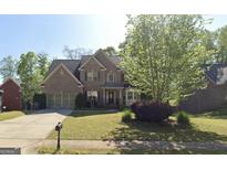 Traditional brick two-story home with well-manicured front yard and attached two-car garage at 145 Windward Hls, Mcdonough, GA 30253