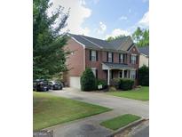 Two-story brick home featuring a well-manicured lawn, attached garage, and a comfortable front porch at 2667 Hampton Park Dr, Marietta, GA 30062