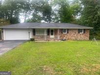 Charming brick home with a well-manicured lawn and attached garage, perfect for comfortable living at 785 Ne South Pine St, Conyers, GA 30012