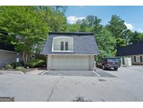 Two-car garage with door to the unit's exterior balcony and black SUV parked to the side on a sunny day at 5490 Chemin De Vie, Sandy Springs, GA 30342
