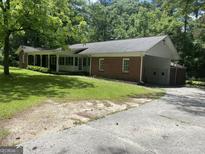 Charming brick home featuring an attached garage and a sprawling front yard with mature trees at 2934 Union Grove Rd, Conyers, GA 30012