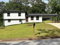 Charming two-story home with a manicured lawn, a carport, and freshly painted exterior at 7340 Chalk Way, Riverdale, GA 30296