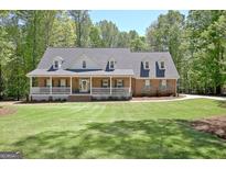 Inviting brick home featuring a charming front porch and lush green lawn at 315 Antebellum Way, Fayetteville, GA 30215