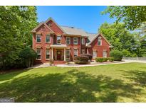 Charming two-story red brick home with a well-manicured lawn, lush landscaping, and mature trees at 255 Hidden Lake Dr, Fayetteville, GA 30215