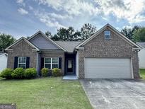 Charming single-story brick home with a well-manicured lawn, an attached two-car garage and welcoming curb appeal at 6703 Biscayne Blvd, Rex, GA 30273