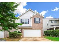 Two-story home featuring a brick and siding exterior, two-car garage, and manicured landscaping at 1562 Onalee Dr, Hampton, GA 30228