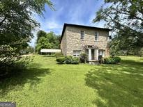 Stone house with a lush green lawn and mature trees around the property at 1085 Pleasant Hill Nw Rd, Conyers, GA 30012