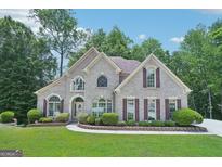 Stunning brick home featuring arched windows, a manicured lawn, and mature trees at 765 Brooks Cir, Stone Mountain, GA 30087
