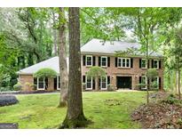 Two-story brick home with black shutters and manicured front lawn, surrounded by lush trees at 335 Cedar Ln, Fayetteville, GA 30214