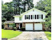 Charming two-story home with brick and white siding and a two-car garage and well maintained front lawn at 1328 Kimlie Ln, Decatur, GA 30035