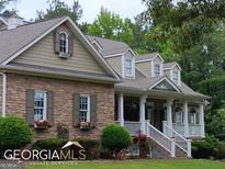 Charming home featuring a stone facade, inviting front porch, dormer windows, and lush landscaping at 531 Grant Rd, Brooks, GA 30205