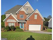Charming two-story brick home with a manicured lawn, bright blue door, and attached two-car garage at 3932 Misty Lake, Ellenwood, GA 30294