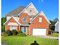 Charming two-story brick home with a well-manicured lawn and bright blue trim around the front door and garage at 3932 Misty Lake, Ellenwood, GA 30294