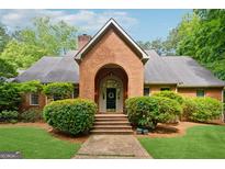 Charming brick home featuring a brick archway entrance, beautiful landscaping, and a well-maintained front yard at 9255 Betony Wood Trl, Jonesboro, GA 30236