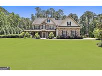 Beautiful stone-and-siding home with a large, manicured lawn and a charming covered front porch at 101 Sumner Place Ct, Peachtree City, GA 30269