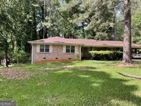 Charming single story brick home with shutters surrounded by lush landscaping at 4116 Warrior Trl, Stone Mountain, GA 30083