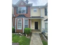 Charming townhome featuring a brick and siding facade with a well-manicured lawn and inviting entryway at 1464 Riverrock Trl, Riverdale, GA 30296