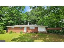 Charming brick ranch-style home with a car port nestled among mature trees in a serene setting at 305 Flat Shoals Church Rd, Stockbridge, GA 30281