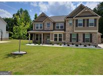 Charming two-story home featuring brick accents, a well-manicured lawn, and a welcoming covered front porch at 436 Lothbury Ave, Locust Grove, GA 30248