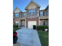 A townhouse featuring mixed exteriors: brick, stone, tan painted siding, with blue shutters and an attached garage at 5257 Carrie Dr, Morrow, GA 30260