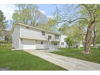 Charming gray two-story home featuring an attached garage and well-maintained front lawn, and concrete stairs at 474 Autumn Dr, Riverdale, GA 30274