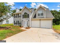 Two-story home showcasing a well-manicured lawn, two-car garage, and a welcoming entrance at 4506 White Rd, Douglasville, GA 30135