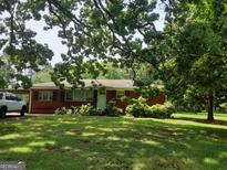Charming red brick home with a lush front yard and mature shade trees offers great curb appeal at 856 New Hope Rd, Fayetteville, GA 30214