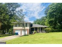 Charming two-story home with a well-manicured front yard and a covered porch, nestled among lush trees at 443 S Rays Rd, Stone Mountain, GA 30083