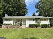 Charming one-story home with a white brick exterior, manicured lawn, and lush landscaping at 3095 Holbrook Sw Dr, Marietta, GA 30060