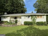Charming single-story home with white brick, lush landscaping, and a welcoming front porch area at 3095 Holbrook Sw Dr, Marietta, GA 30060