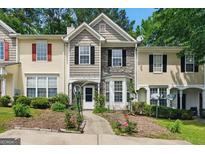 Charming townhome featuring a stone facade, black shutters, and a beautifully landscaped front yard at 1689 Camden Forrest Way, Riverdale, GA 30296