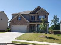 Charming two-story home featuring a brick facade, well-manicured lawn, and a two-car garage, set beneath a clear blue sky at 878 W Union Grove Cir, Auburn, GA 30011
