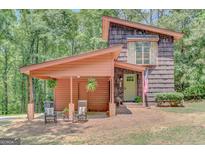 Unique home with wood facade, covered parking, and inviting front porch showcasing American flag at 29 Clark Pl, Whitesburg, GA 30185