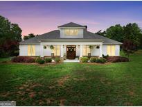 Charming home with a manicured lawn, rocking chair front porch, and inviting curb appeal at dusk at 377 Parker Rd, Mcdonough, GA 30252