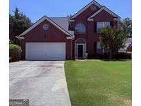 Charming two-story brick home with attached two car garage and well-manicured front lawn at 2990 Haynes Club Cir, Grayson, GA 30017