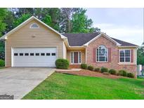 Charming home featuring a two-car garage, well-manicured lawn, and a mix of brick and siding accents at 221 Ashley Oaks, Mcdonough, GA 30253