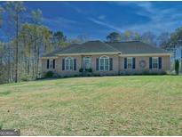 Charming brick home featuring a well-manicured lawn and dark shutters on a sunny day at 809 Mcbean Ct, Mcdonough, GA 30252