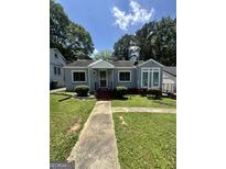 Charming single-story home with a walkway, manicured lawn, and mature trees at 1730 Emerald Sw Ave, Atlanta, GA 30310