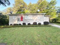 Charming single-story home with a red front door and well-manicured lawn and landscaping at 2159 Holly Hill Dr, Decatur, GA 30032
