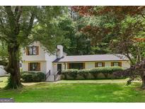 Charming two-story home with a well-manicured lawn, surrounded by lush trees, features black trimmed windows and wood-look shutters at 3308 Quail Sw Run, Marietta, GA 30008