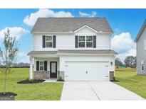 Charming two-story home featuring white siding, a two-car garage, and a beautifully landscaped front yard at 307 Limestone Circle, Conyers, GA 30013