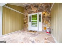 Inviting entrance area with stone floors, walls, and a white front door at 7358 S Mitchell Ct, Villa Rica, GA 30180