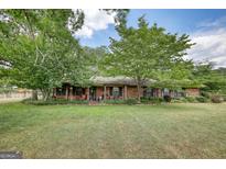 Charming brick home with a lovely front porch and mature trees in a large manicured lawn at 1024 Bethany Rd, Covington, GA 30016