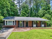 Charming brick ranch with manicured lawn and black shutters, set against a backdrop of lush trees at 1356 Lori Ct, Conley, GA 30288