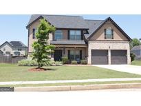 Charming two-story home with a well-manicured lawn and a two-car garage. A lovely tree adds to the curb appeal at 524 Harmony Way, Locust Grove, GA 30248