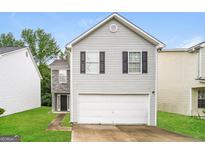 Charming two-story home with gray siding, black shutters, and a two-car garage at 1577 Keystone Dr, Conley, GA 30288