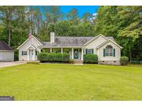Charming one-story home featuring a lush front lawn, cozy porch with decorative details, and traditional architectural elements at 229 Lafayette St, Locust Grove, GA 30248