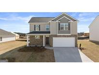 Two-story home featuring a two-car garage, brick accents, and a well-manicured lawn at 162 Aster Ave, Locust Grove, GA 30248