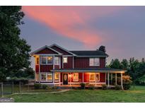 Charming two-story home featuring a inviting front porch, lush green lawn, and picturesque sunset backdrop at 68 Riveree Rd, Brooks, GA 30205
